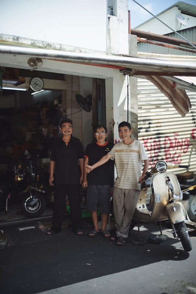Anh em trước tiệm Vespa Quý Bảy Hổ với chiếc Vespa vàng champagne